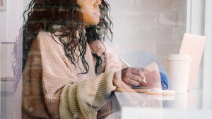 Lady writing and looking out of the window relaxed