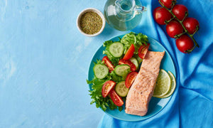Salmon, salad with a side of tomatoes and water