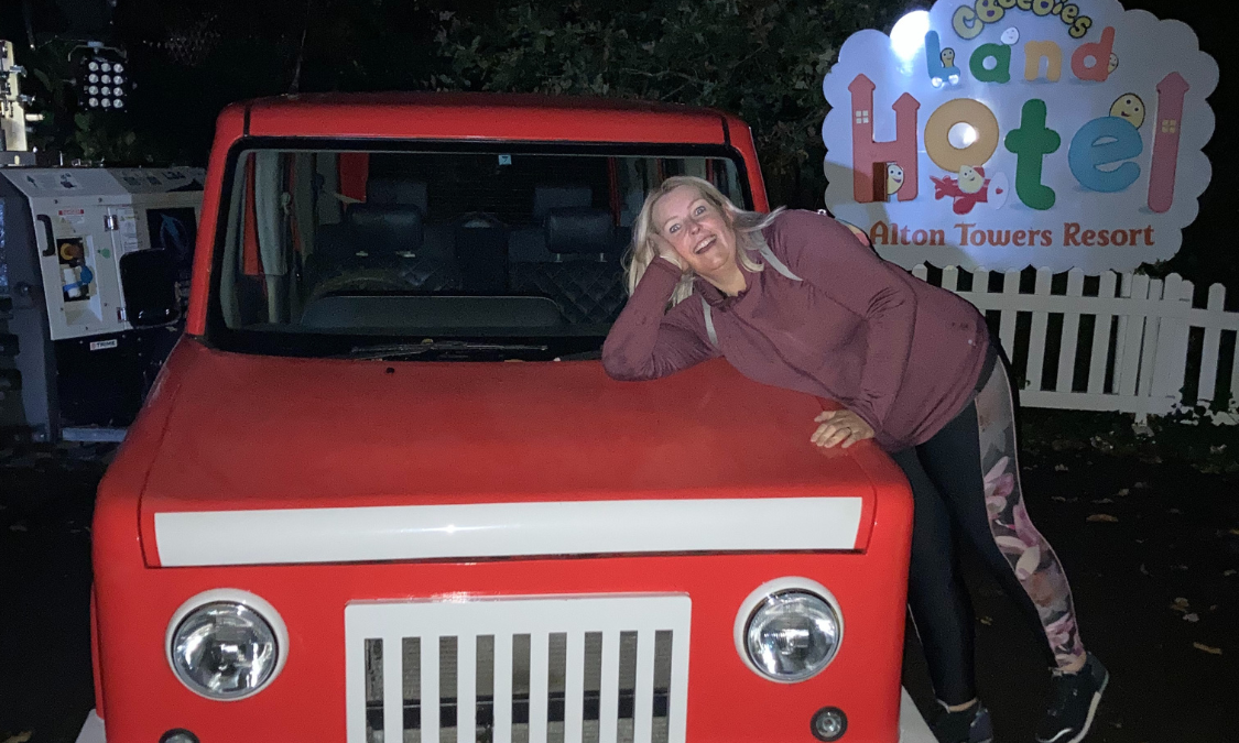 Sarah leaning on a red toy car at Alton Towers