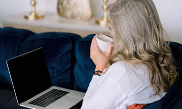 Lady looking at her laptop and drinking from a mug