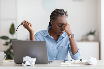 Lady stressed at work holding her head whilst in front of a laptop